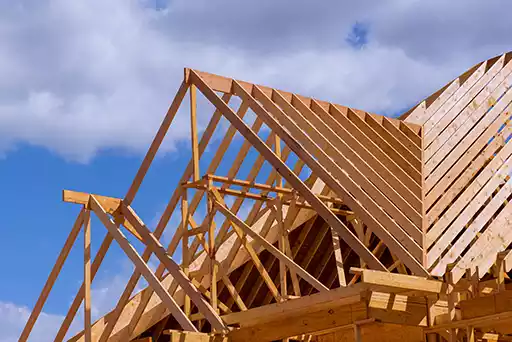 Close up of a residential roof with gray shingles on top of a large, mid-class home