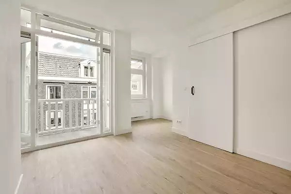 Two windows side by side inside of a home with white, transparent curtains on either side