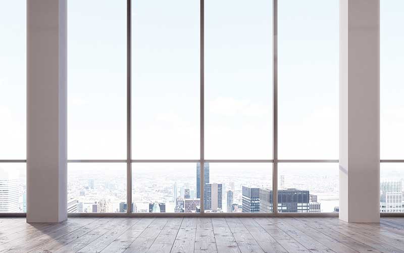 Empty office-like room with a large window overlooking a city landscape