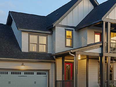 Front of a typical looking home with light gray Mastic siding as nightfall begins to set in