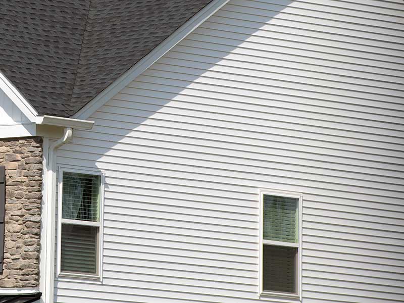 Close up of a two-story home's white siding